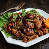Chilli chicken in a dark glossy sauce with onions